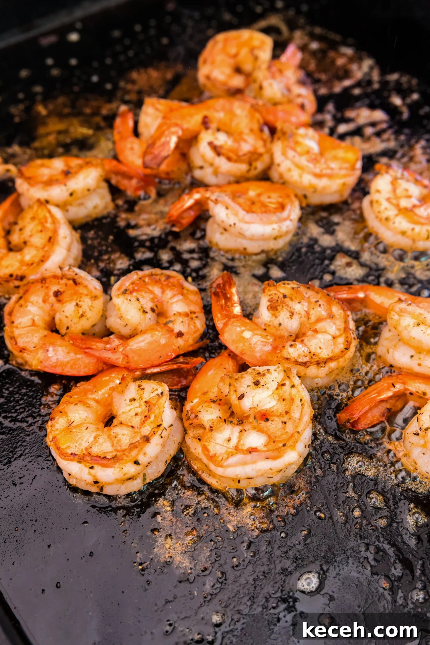 Crispy Blackstone Grilled Shrimp with Garlic Butter Sauce 10 Close-up of shrimp on a flat-top griddle, fully cooked to a golden brown with slightly curled edges.