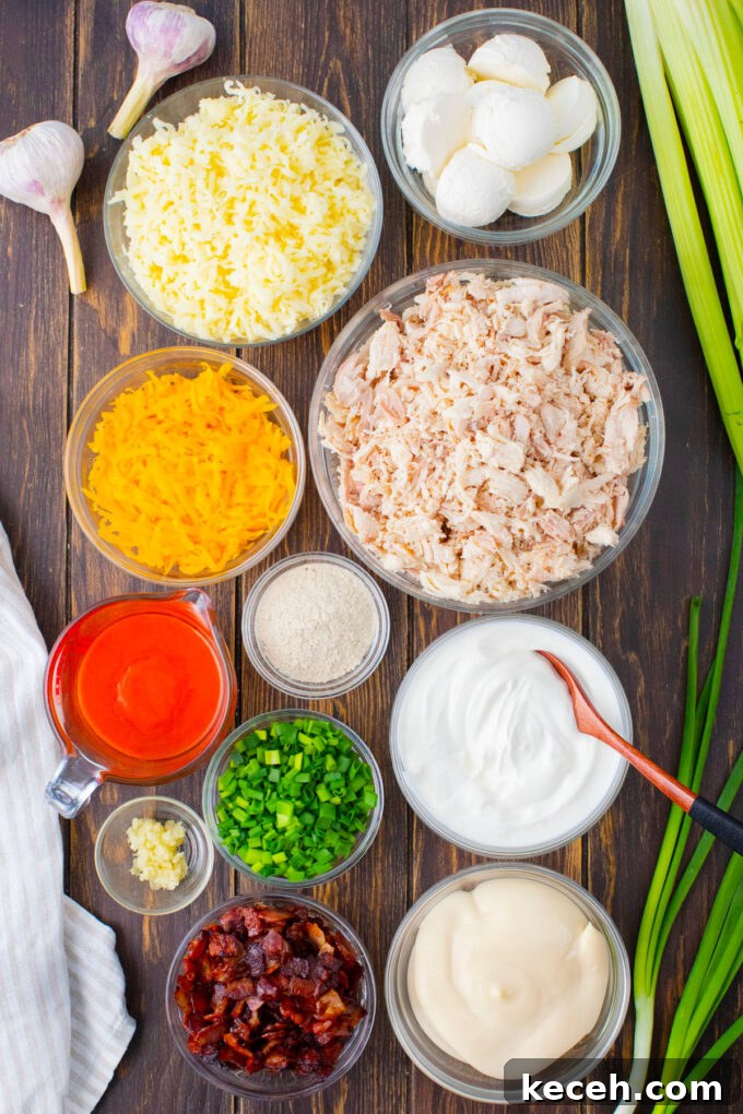 One-Bowl Buffalo Chicken Dip Recipe for Game Day 4 Overhead shot of Buffalo crack chicken dip ingredients in bowls on a wooden table.
