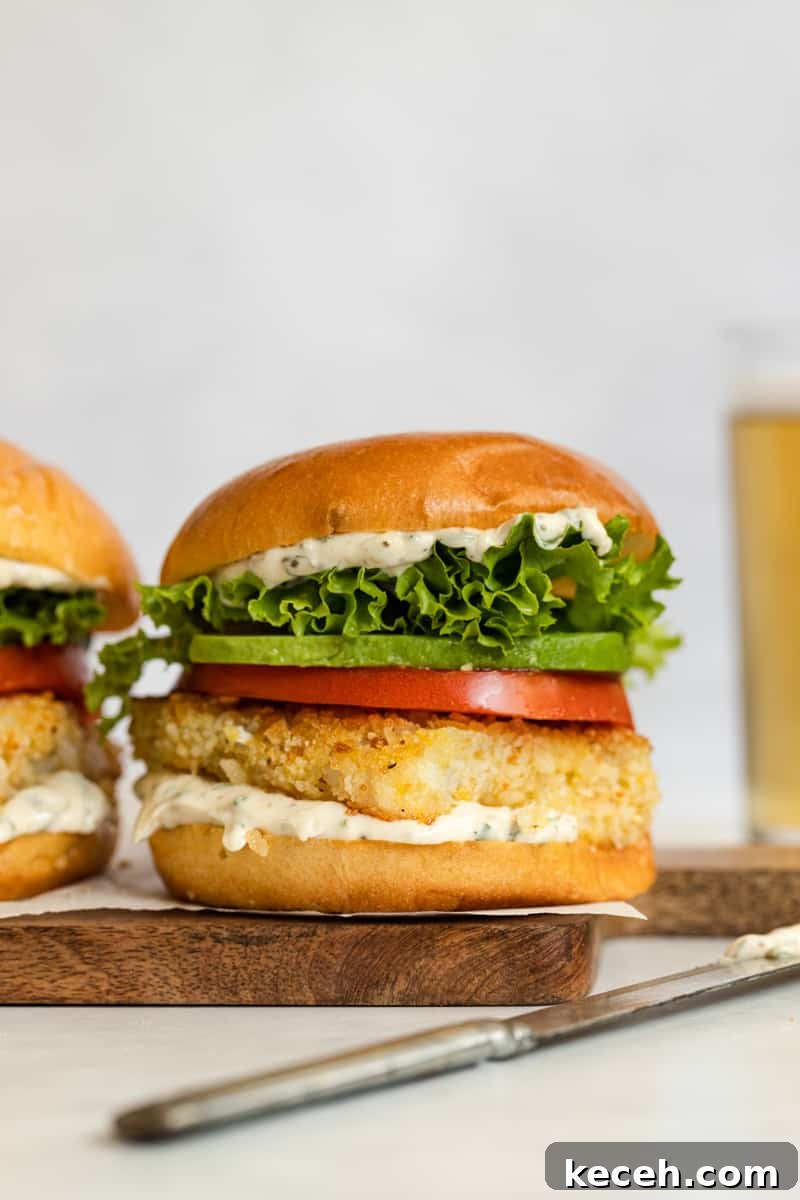 Crispy Oven-Baked Fish Sandwiches You’ll Crave 2 Crispy fried fish sandwich with tomato, avocado, and lettuce on a toasted bun