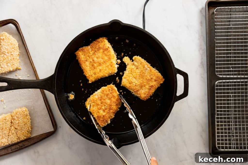 Crispy Oven-Baked Fish Sandwiches You’ll Crave 6 Breaded fish fillets frying in a cast iron skillet until golden and crispy