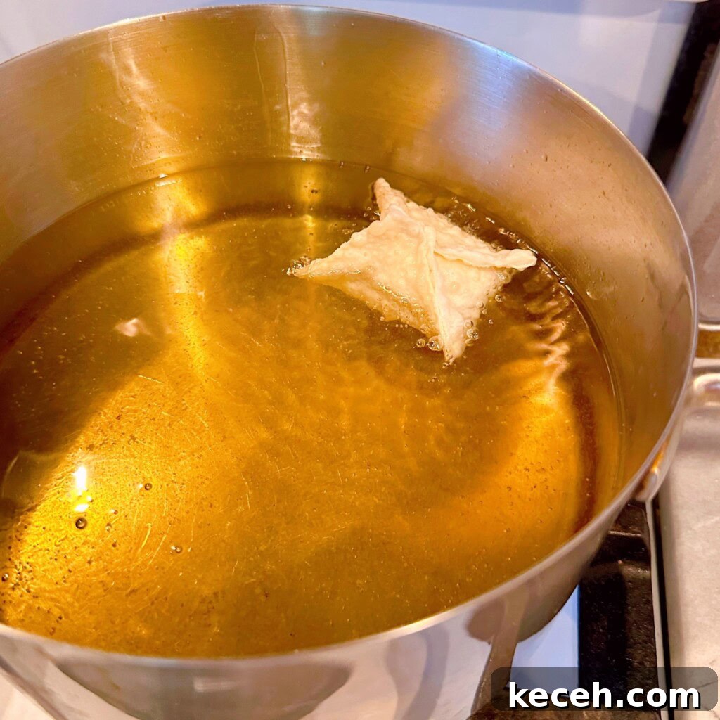 Classic Crab Rangoon Recipe: Crispy Crab & Cream Cheese Wontons 7 Frying wonton in heated oil in a large sauce pan on the stove top.
