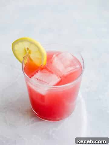 Pink grapefruit hibiscus cocktail in glass with ice.