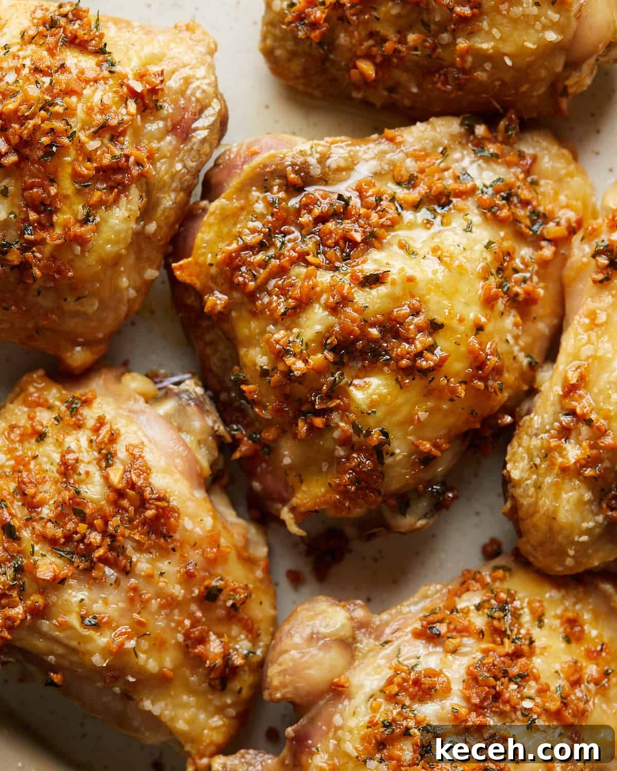 Crispy Baked Garlic Butter Chicken Thighs 2 Up-close overhead photo of garlic butter chicken thighs on a plate, coated in rich garlic butter sauce and finished with fresh herbs, showcasing juicy, golden-browned chicken thighs ready to serve.