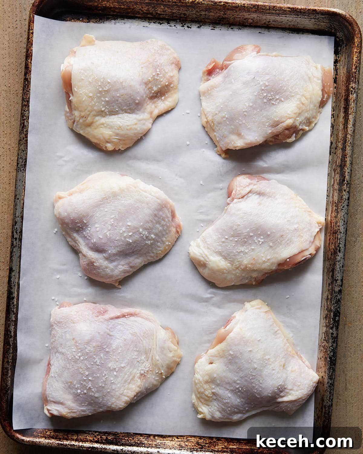 Crispy Baked Garlic Butter Chicken Thighs 5 Overhead shot of dry brine chicken thighs seasoned with kosher salt, resting on a tray before cooking to enhance flavor and juiciness.