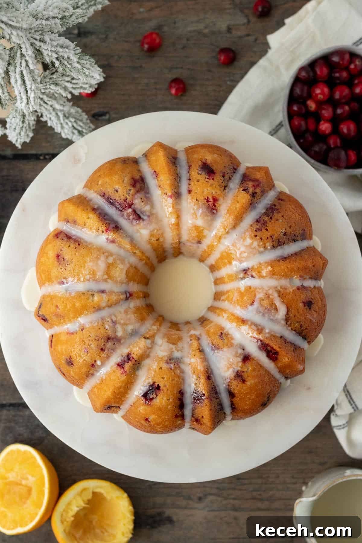 Cranberry-Orange Bundt Cake with Fresh Cranberry Sauce Swirl 3 cranberry orange bundt cake on a white marble cake stand on a wood background