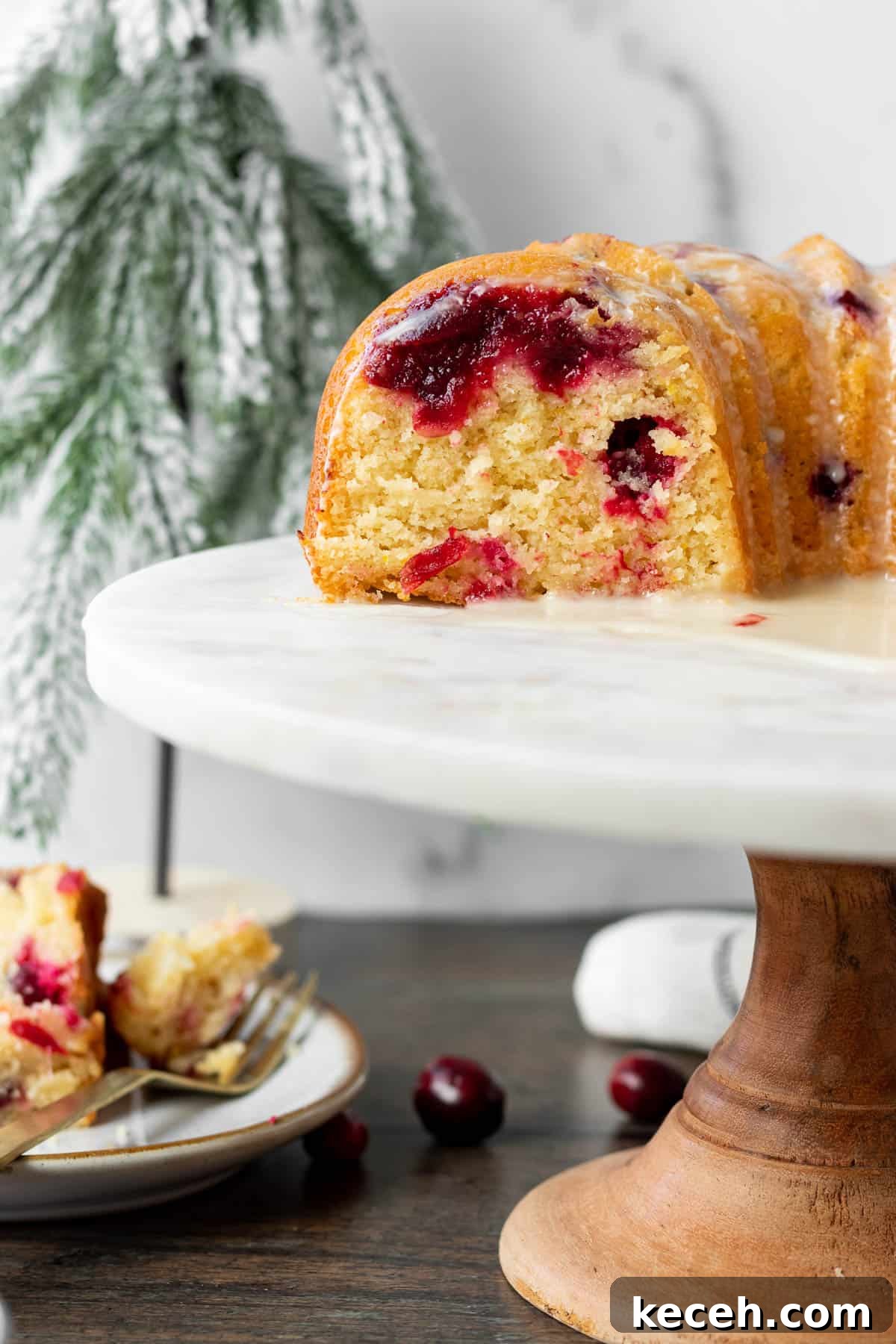 Cranberry-Orange Bundt Cake with Fresh Cranberry Sauce Swirl 8 cut cranberry orange bundt cake on a wood and marble cake stand
