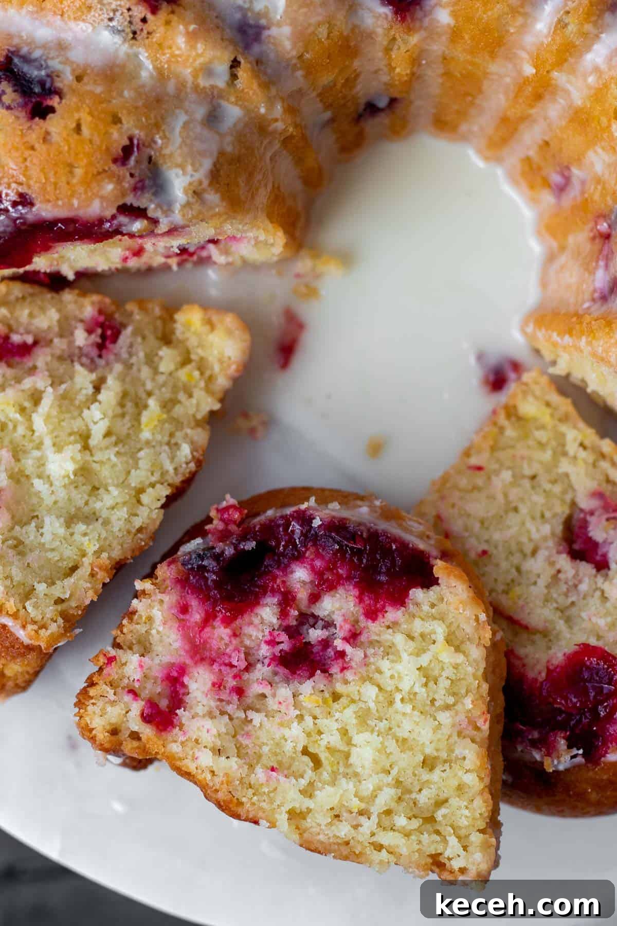 Cranberry-Orange Bundt Cake with Fresh Cranberry Sauce Swirl 9 close up of slices of cranberry orange bundt cake on a white marble stand