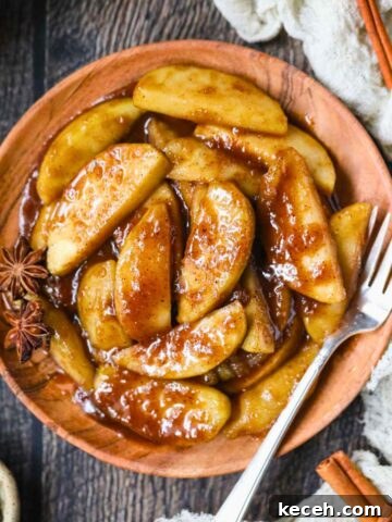 Southern fried apples on a wooden plate sitting on top of a wooden surface.