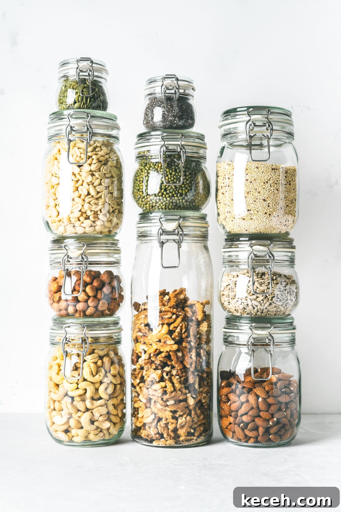 Glass jars stacked filled with low carb panty essential nuts and seeds