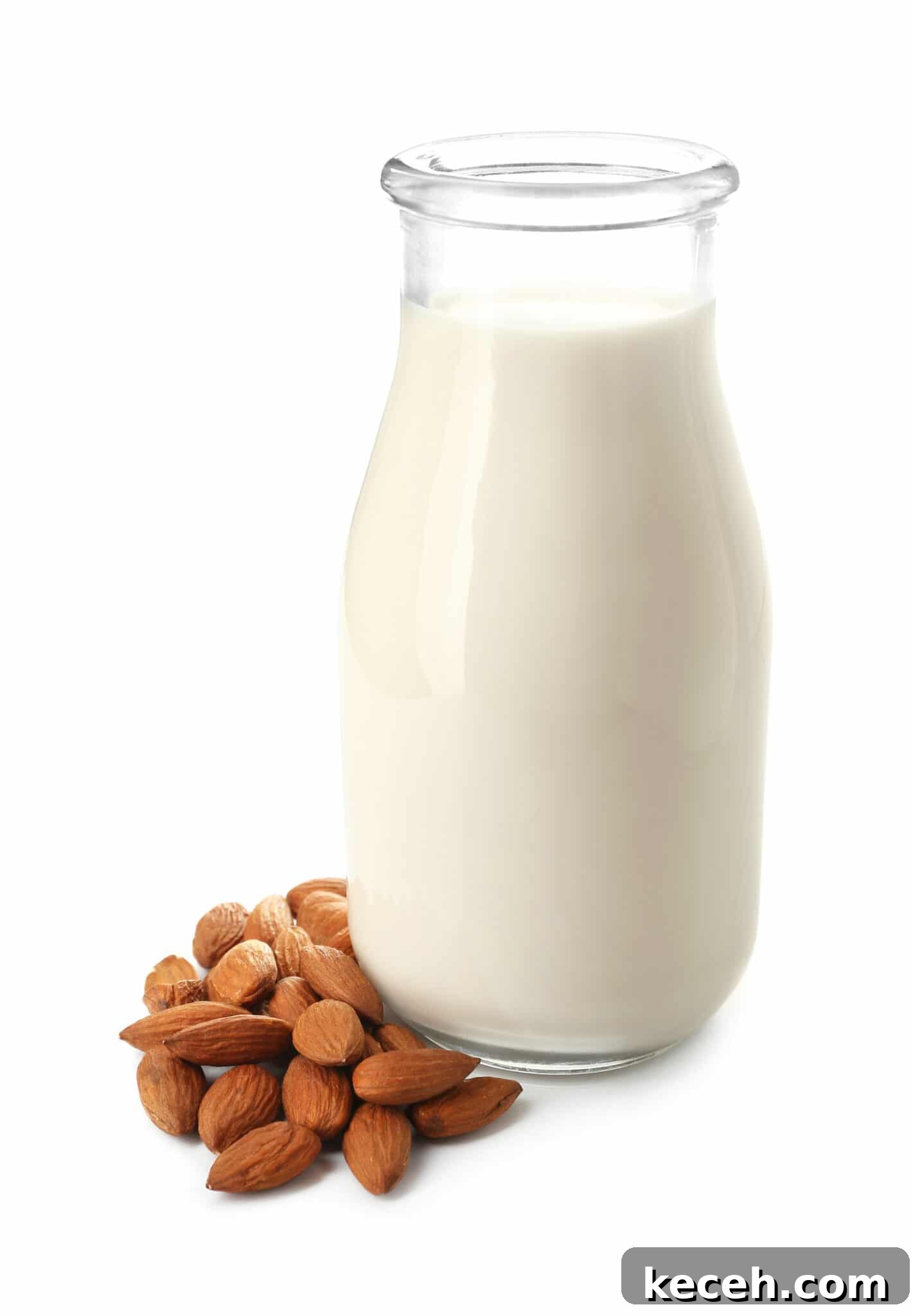 A tall glass bottle of almond milk, with a small pile of almonds beside it.