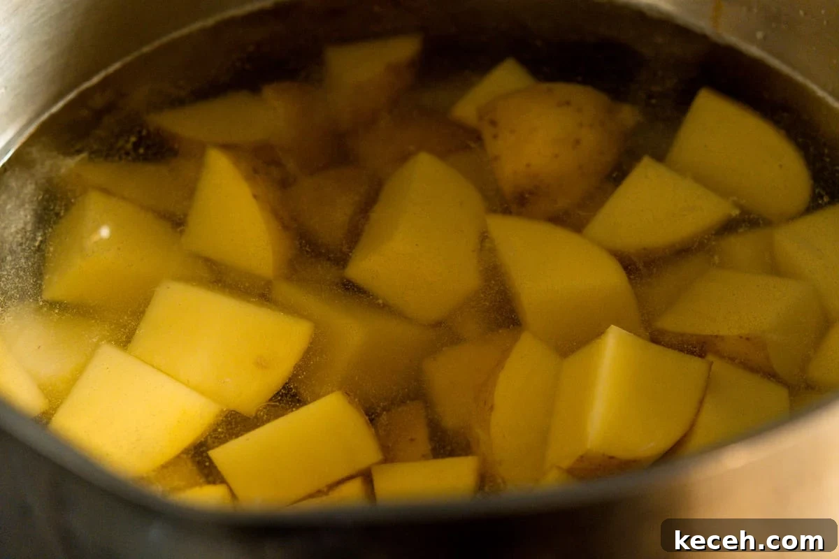 Crispy Rosemary Roasted Potatoes Recipe 4 cubed potatoes covered in water in a saucepan.