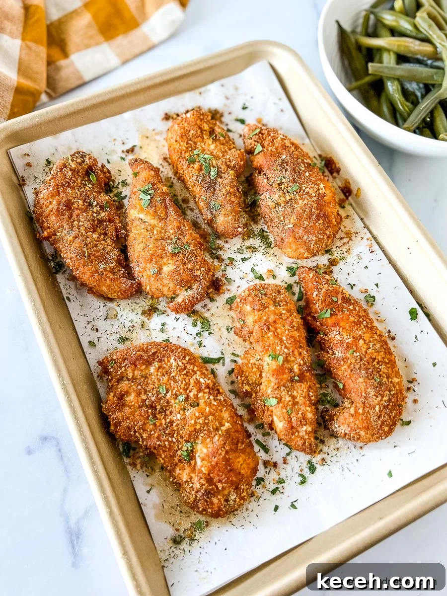 Crispy Shake and Bake Chicken Recipe for Perfect Oven-Fried Crunch 3 Crispy baked panko chicken tenders on parchment lined baking pan.