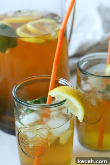 Two glasses of mint tea with pitcher in back.