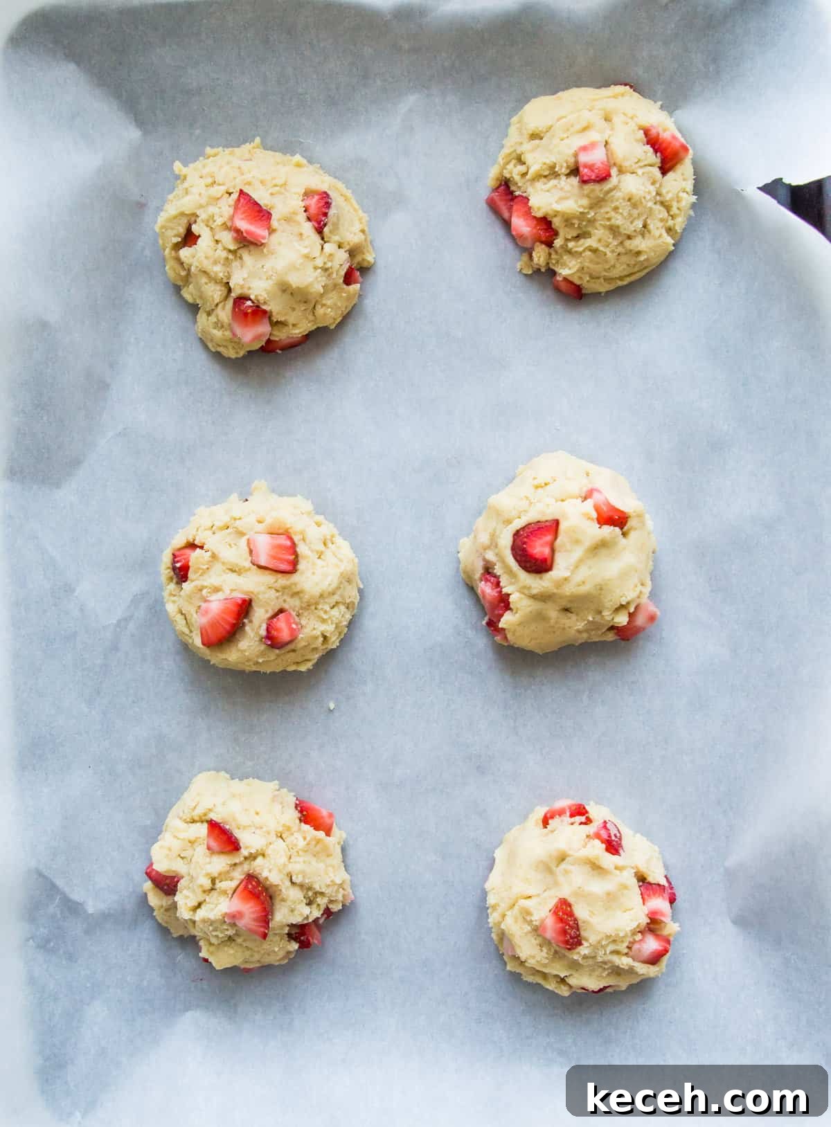 A baking sheet with strawberry cookie dough balls on it.