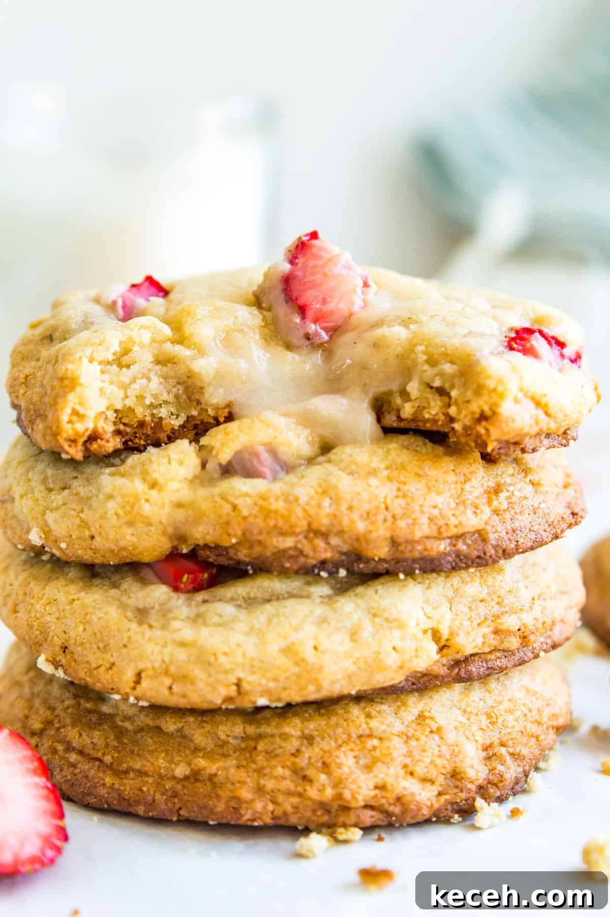 A stack of cheesecake filled strawberry cookies with fresh strawberries around them.
