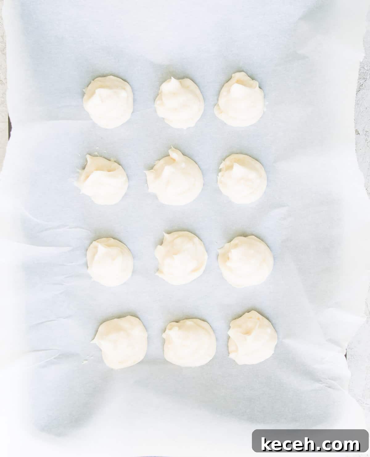 A piece of parchment paper with cream cheese balls on it.