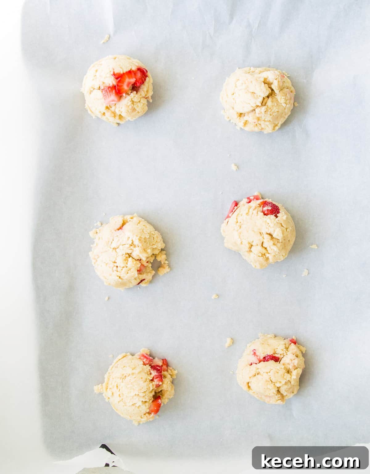 A baking sheet with strawberry cookie dough balls on it.