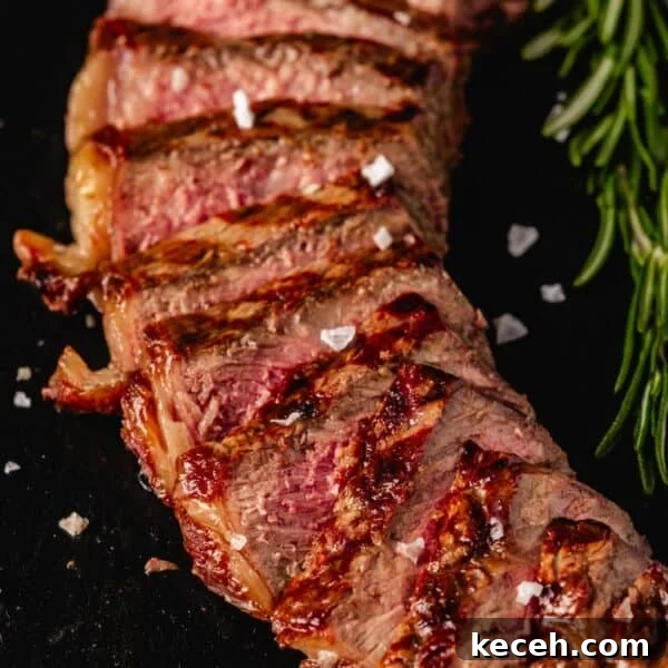 Crispy Air Fryer Steak with Roasted Potatoes & Green Beans 8 Sliced New York strip on black serving platter.