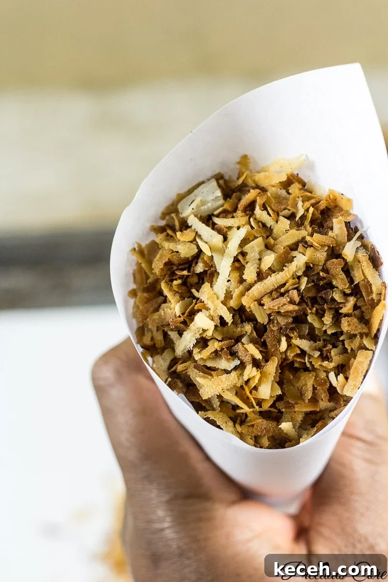 Toasted Coconut Flakes: Sweet Coconut Snack Recipe 2 Person holding a paper cone of toasted coconut flakes.