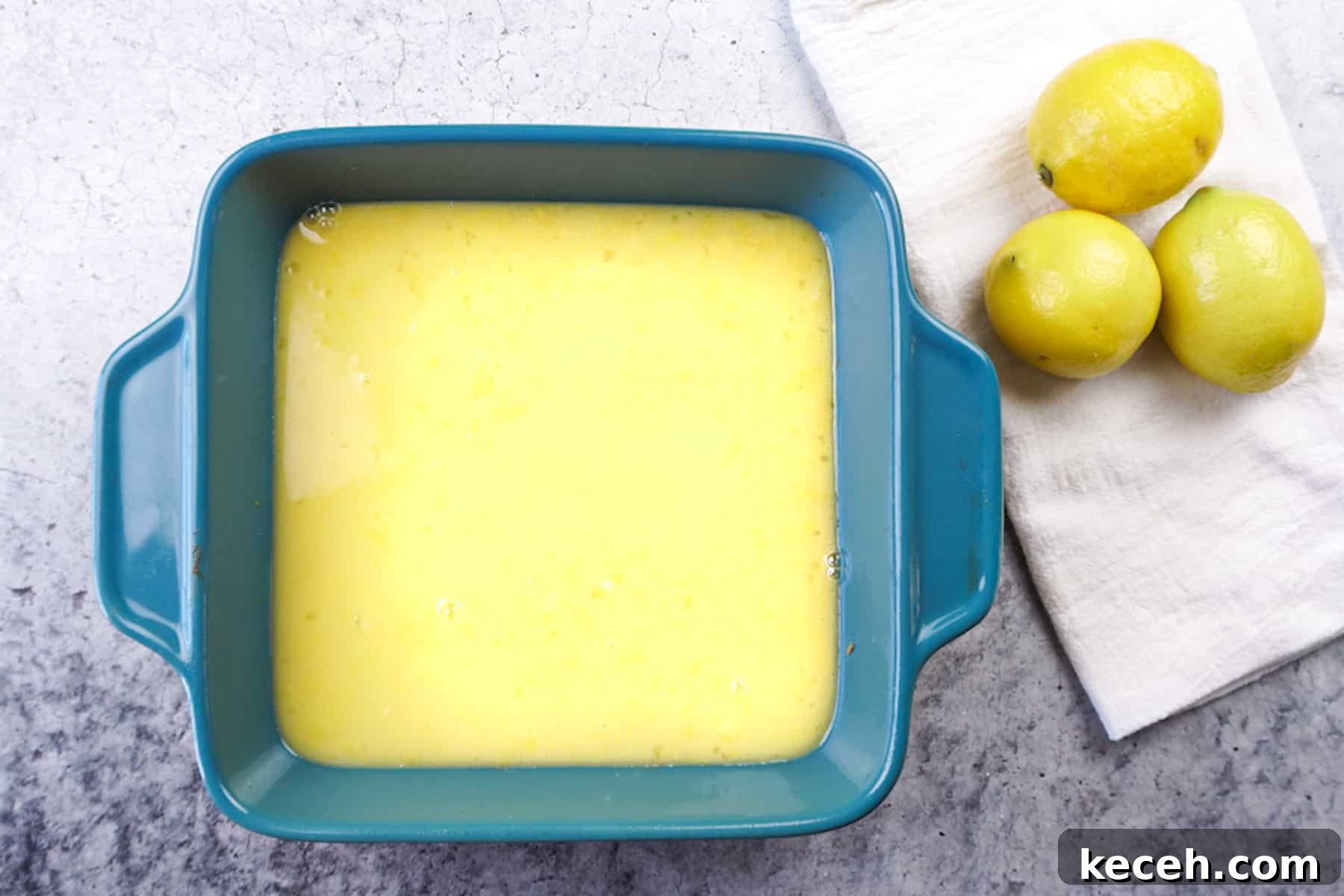 Classic Old-Fashioned Lemon Squares Recipe for Bright Dessert 8 lemon filling poured over crust, unbaked in teal baking dish.