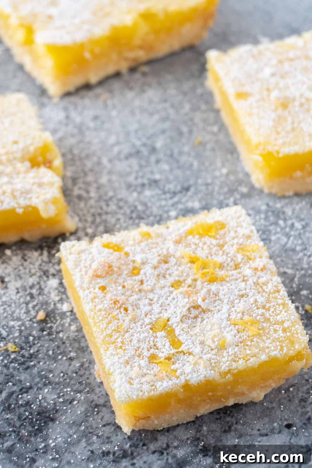 Classic Old-Fashioned Lemon Squares Recipe for Bright Dessert 10 lemon bars on gray counter top sprinkles with powdered sugar.