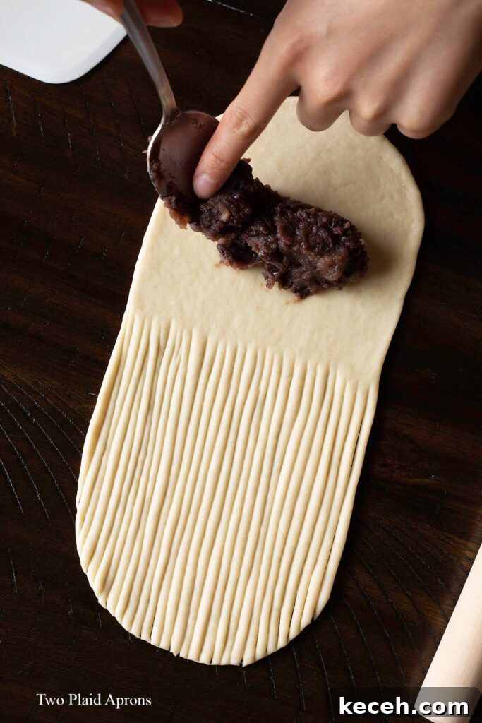 Placing homemade red paste onto the flattened wool bread dough.