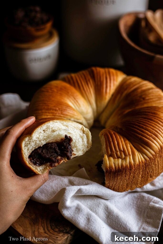 Holding a piece of the wool bread with red bean paste in hand to show filling.