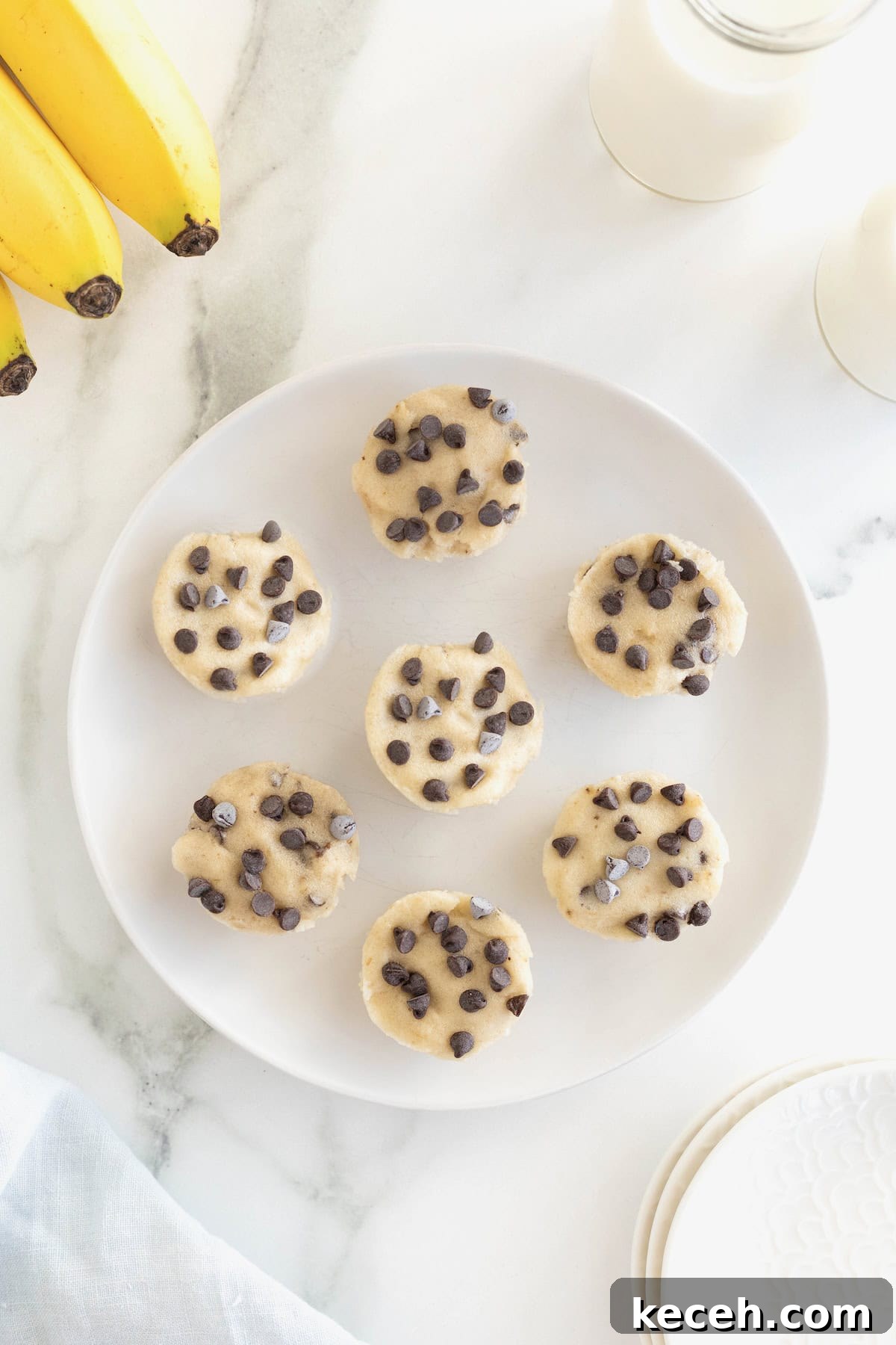 Banana Chocolate Chip Ice Cream Bites — 2-Ingredient Frozen Treats 5 A large white plate with seven ice cream bites arranged in a circle.