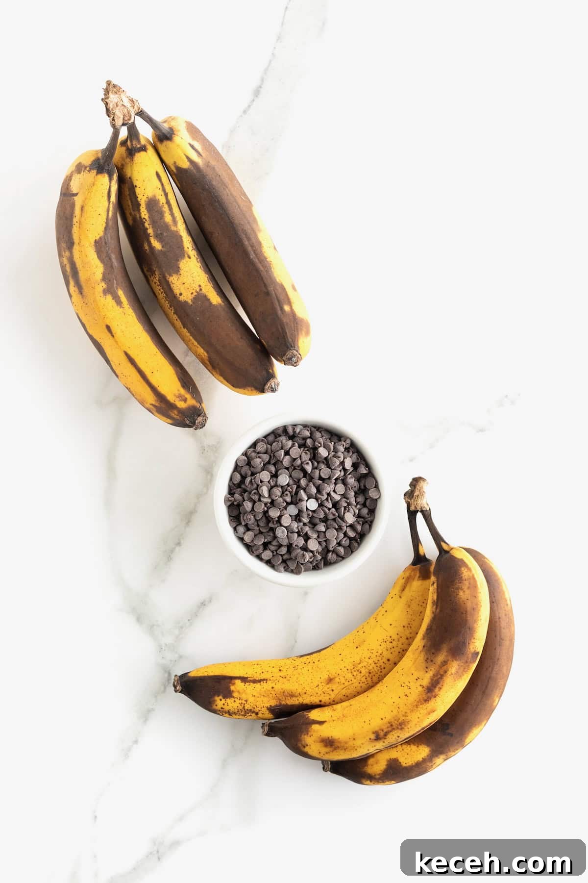 Banana Chocolate Chip Ice Cream Bites — 2-Ingredient Frozen Treats 7 Two bunches of overripe bananas on either side of a small white dish of mini chocolate chips.