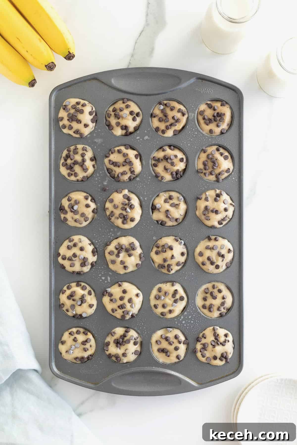 Banana Chocolate Chip Ice Cream Bites — 2-Ingredient Frozen Treats 10 Two-Ingredient Banana Chocolate Chip Ice Cream Bites in an aluminum mini muffin pan on a white marble counter.