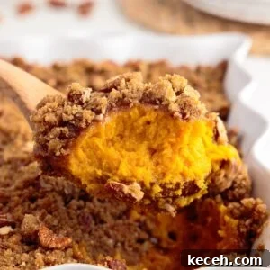 Irresistible Sweet Potato Soufflé Recipe for Holiday Desserts 14 Front close up of a scoop of Sweet Potato Souffle on a wooden spoon.