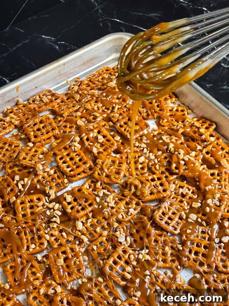 Buttery Toffee Pretzel Snacks: Sweet & Crunchy Recipe 6 Butter toffee being drizzled over the pretzels in a baking sheet.