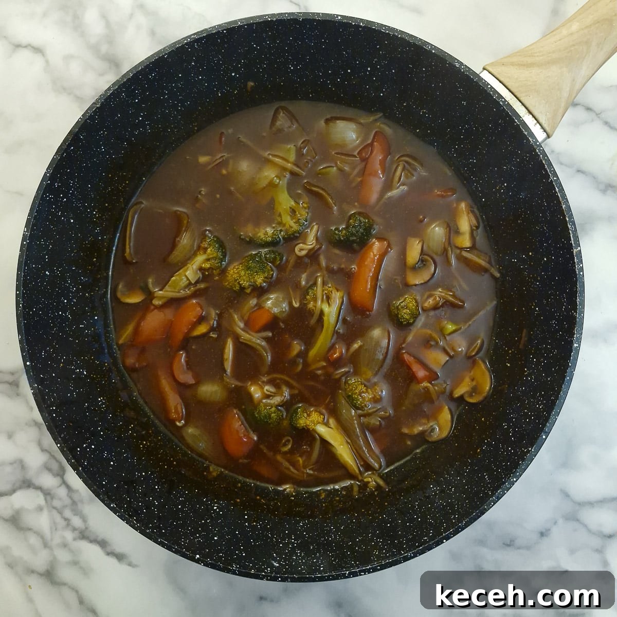 Thickened sauce with vegetales in a wok.