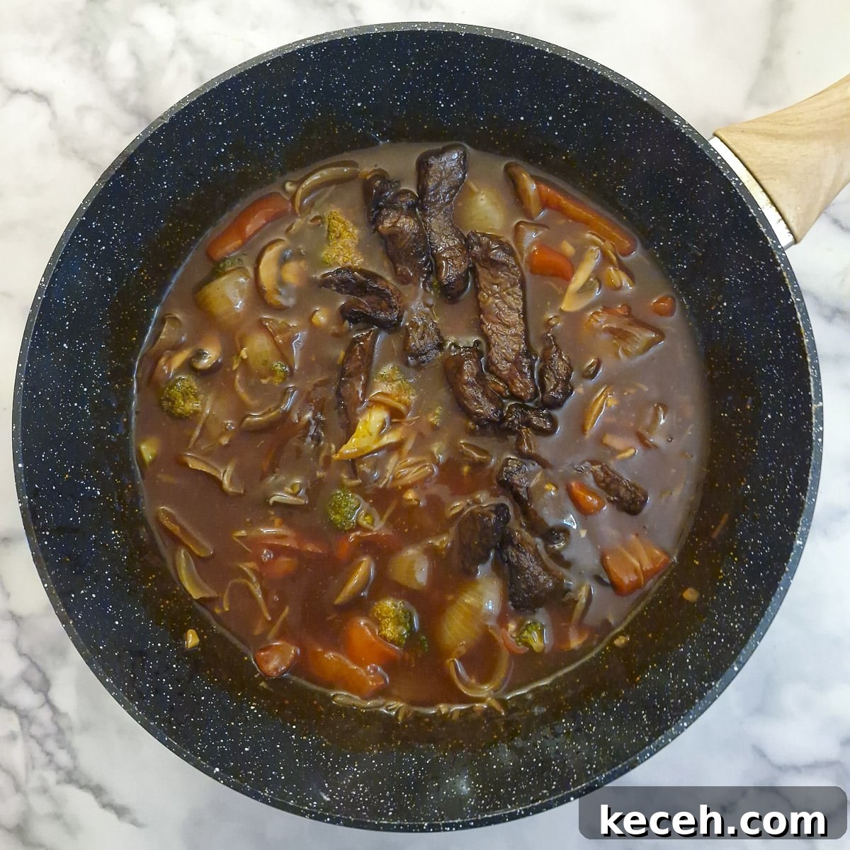 Steak strips added to the sauce in a wok.