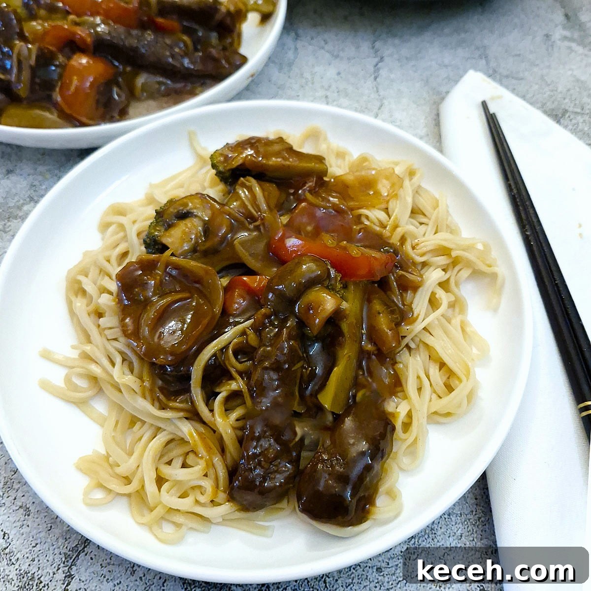 A helping of beef strips in garlic sauce piled on top of a plate of Chinese noodles.