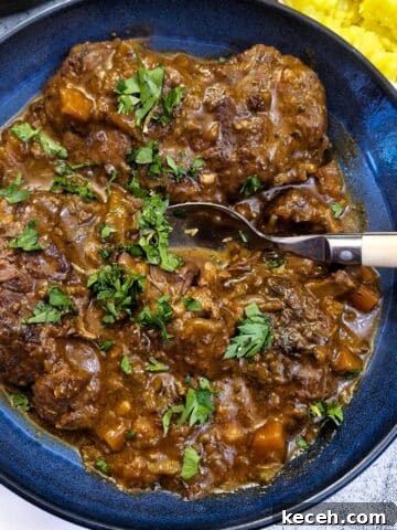 A blue serving dish with beef osso buco garnished with parsley.