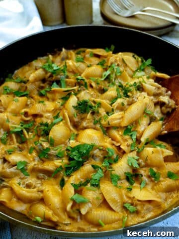 French onion minced beef stroganoff in a frying pan with a large wooden serving spoon.