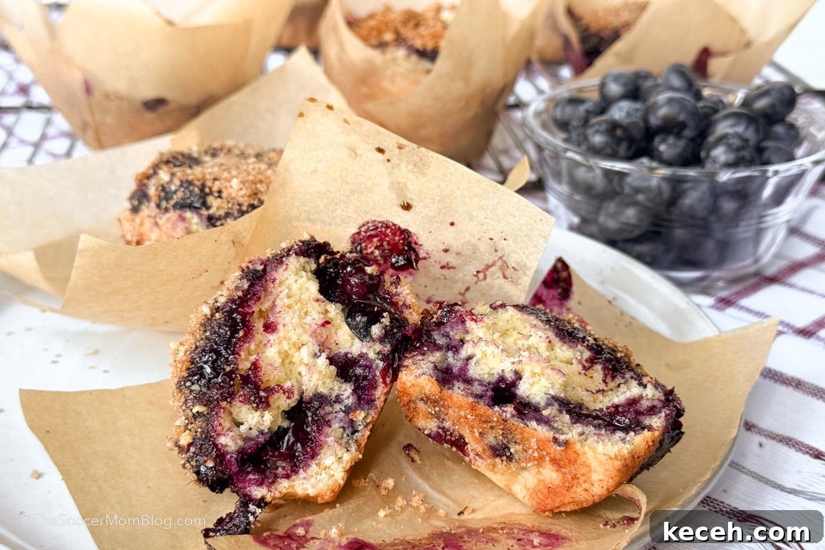 Irresistible Blueberry Crumb Muffins Recipe 3 blueberry muffins on a plate and a bowl of fresh berries.