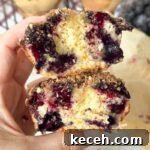 Irresistible Blueberry Crumb Muffins Recipe 9 holding a homemade blueberry muffin that's been cut in half to show detail.