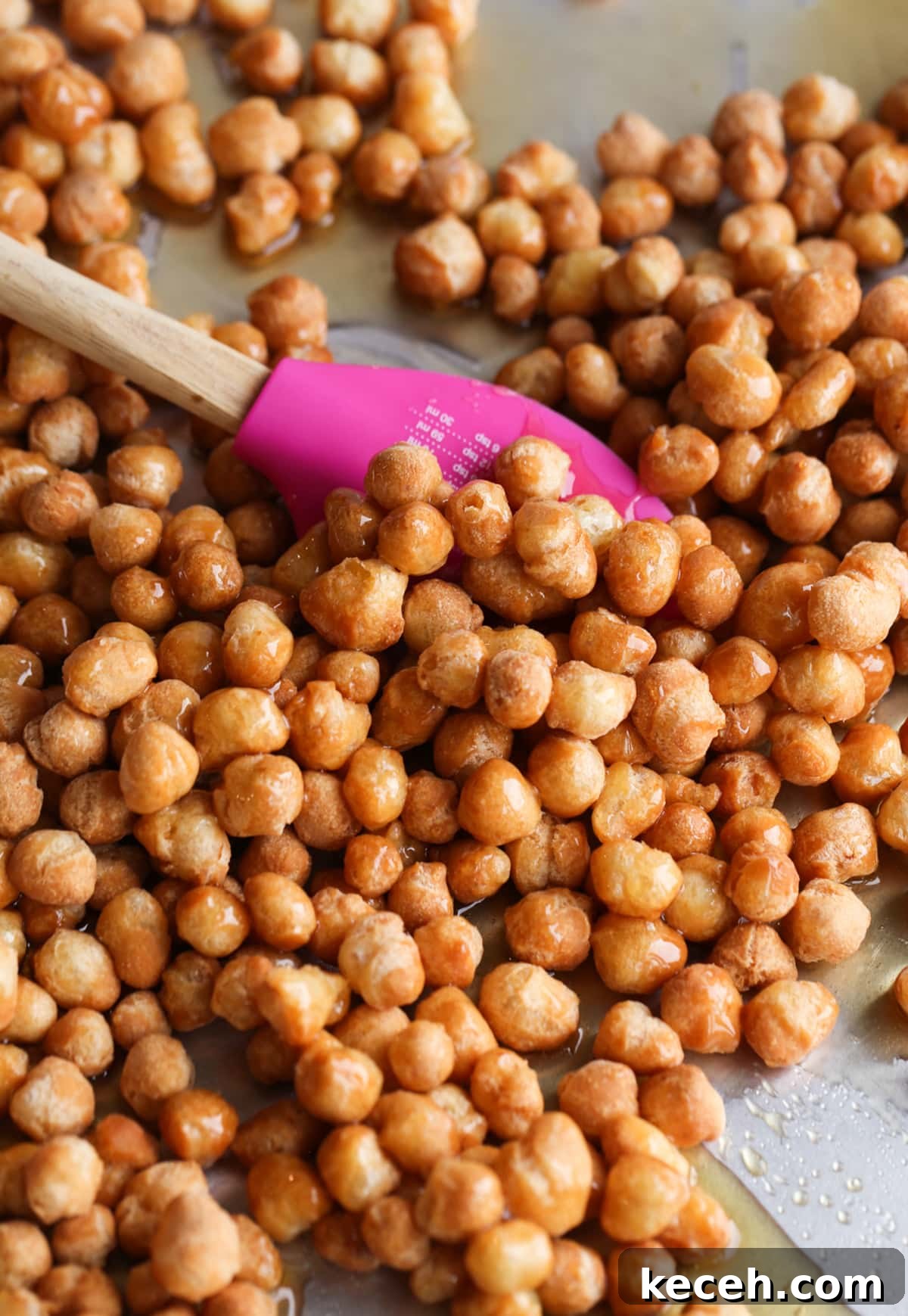 Authentic homemade Struffoli is such a fun Christmas dessert! Cute little balls of fried dough are coated in sweet honey and topped with your favorite holiday sprinkles. Stirring struffoli on a baking sheet coating them with honey