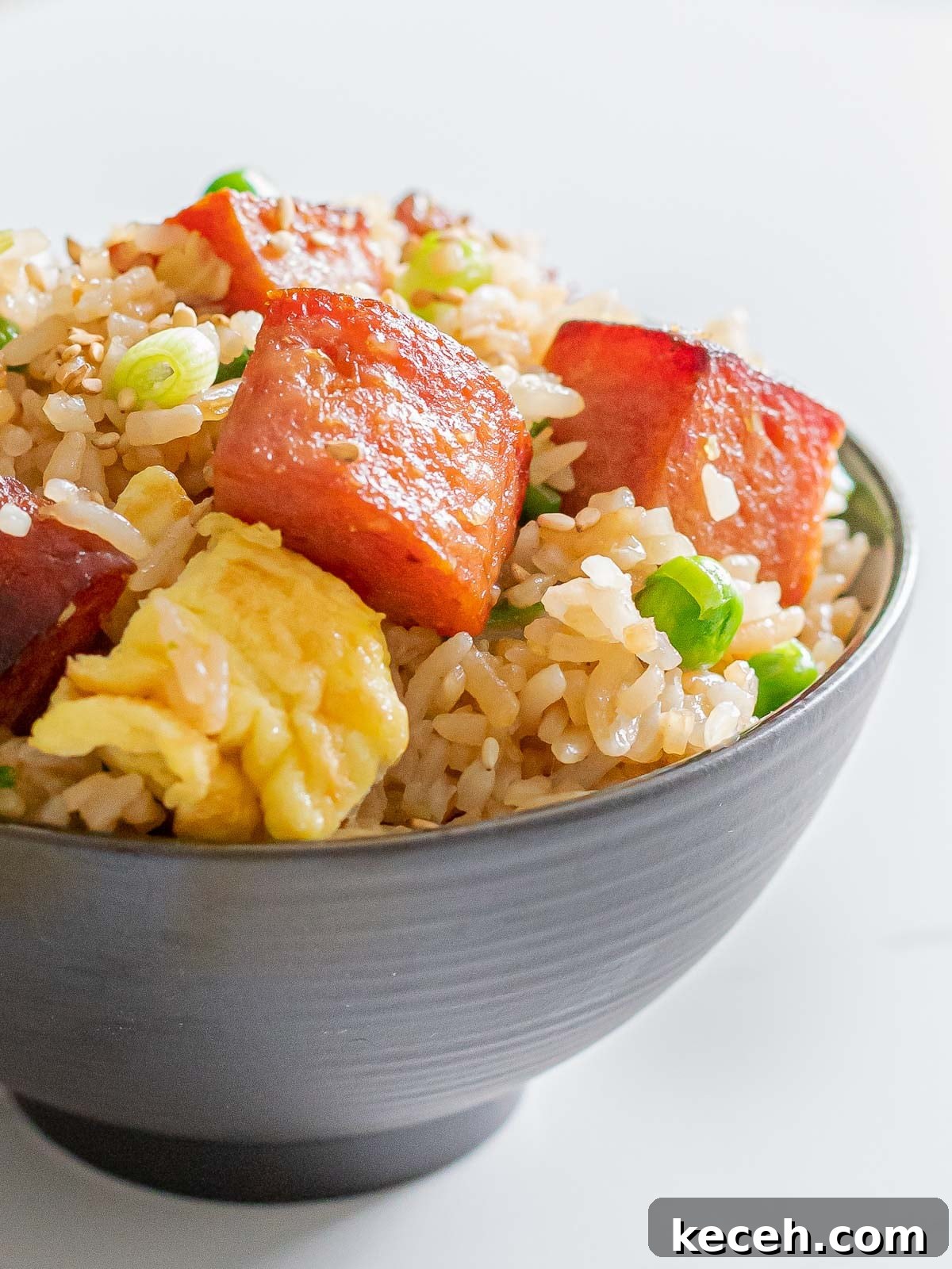 Simple Spam Fried Rice Recipe for Quick Weeknight Meals 3 close up of spam fried rice with eggs, green peas, and rice in a dark bowl