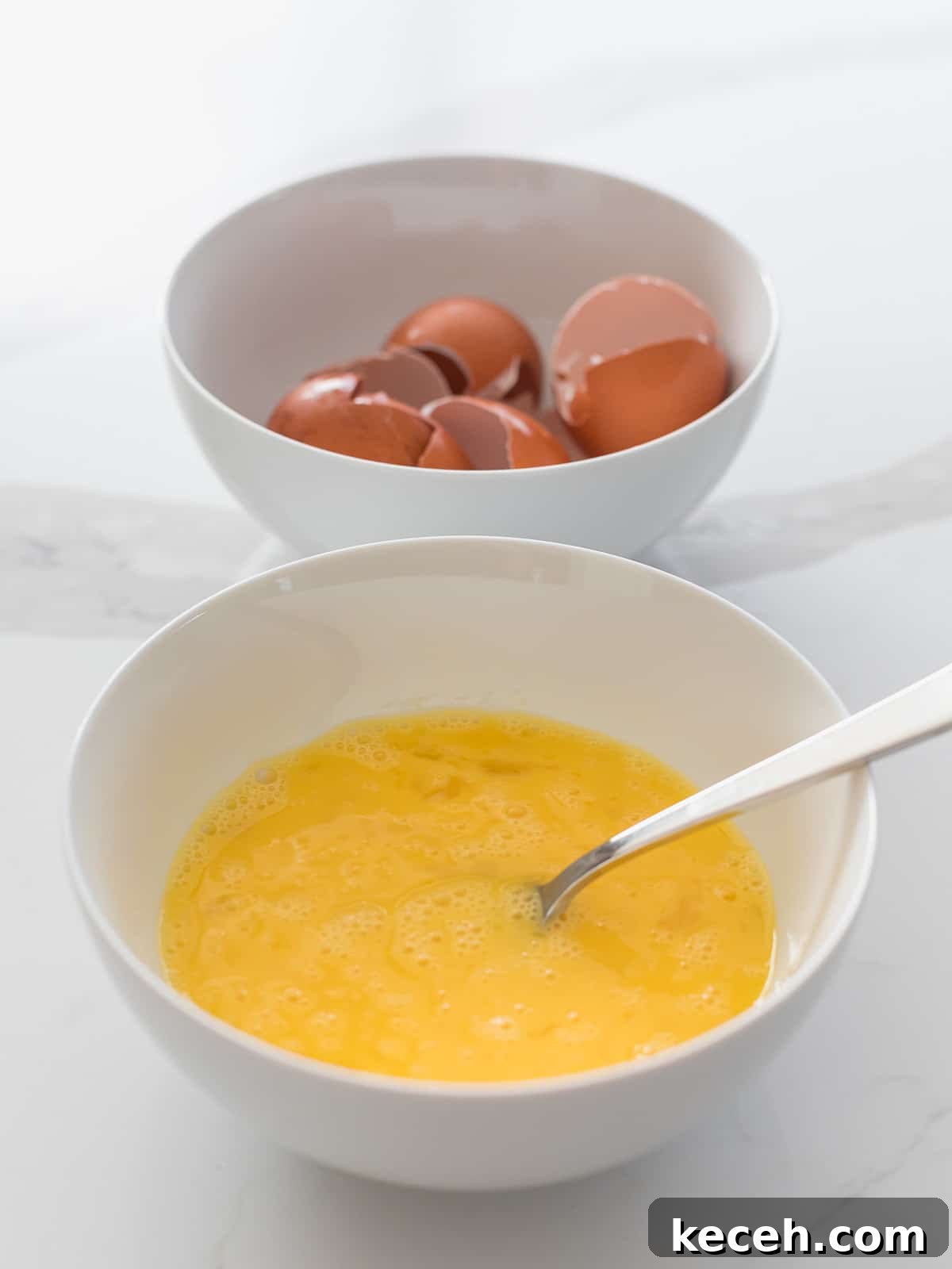 Simple Spam Fried Rice Recipe for Quick Weeknight Meals 6 bowl of beaten eggs with a silver fork next to a bowl filled with egg shells