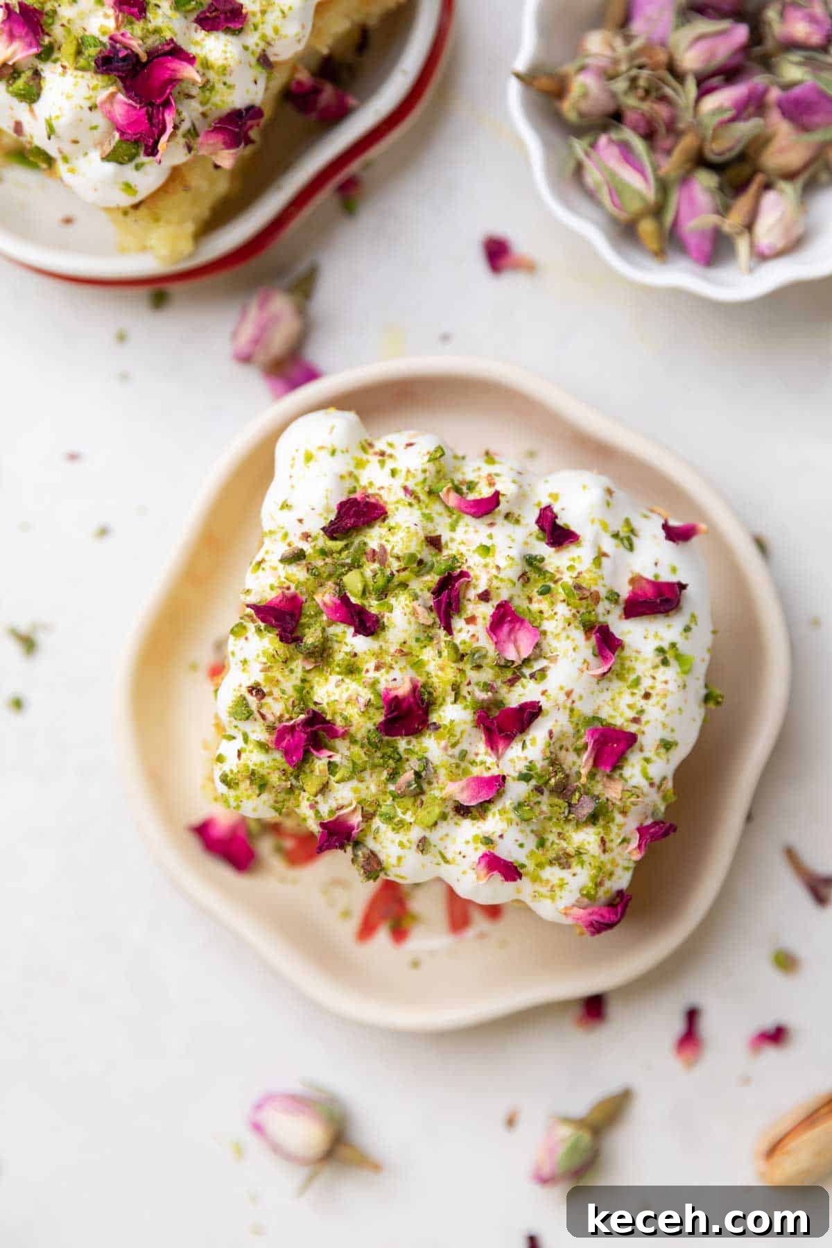 Rasmalai Cake Recipe: How to Make the Classic Indian Dessert Cake 2 a slice of rasmalai cake garnished with cream, crushed nuts and rose petals on a white plate