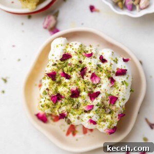 Rasmalai Cake Recipe: How to Make the Classic Indian Dessert Cake 4 a slice of rasmalai cake garnished with cream, crushed nuts and rose petals on a white plate