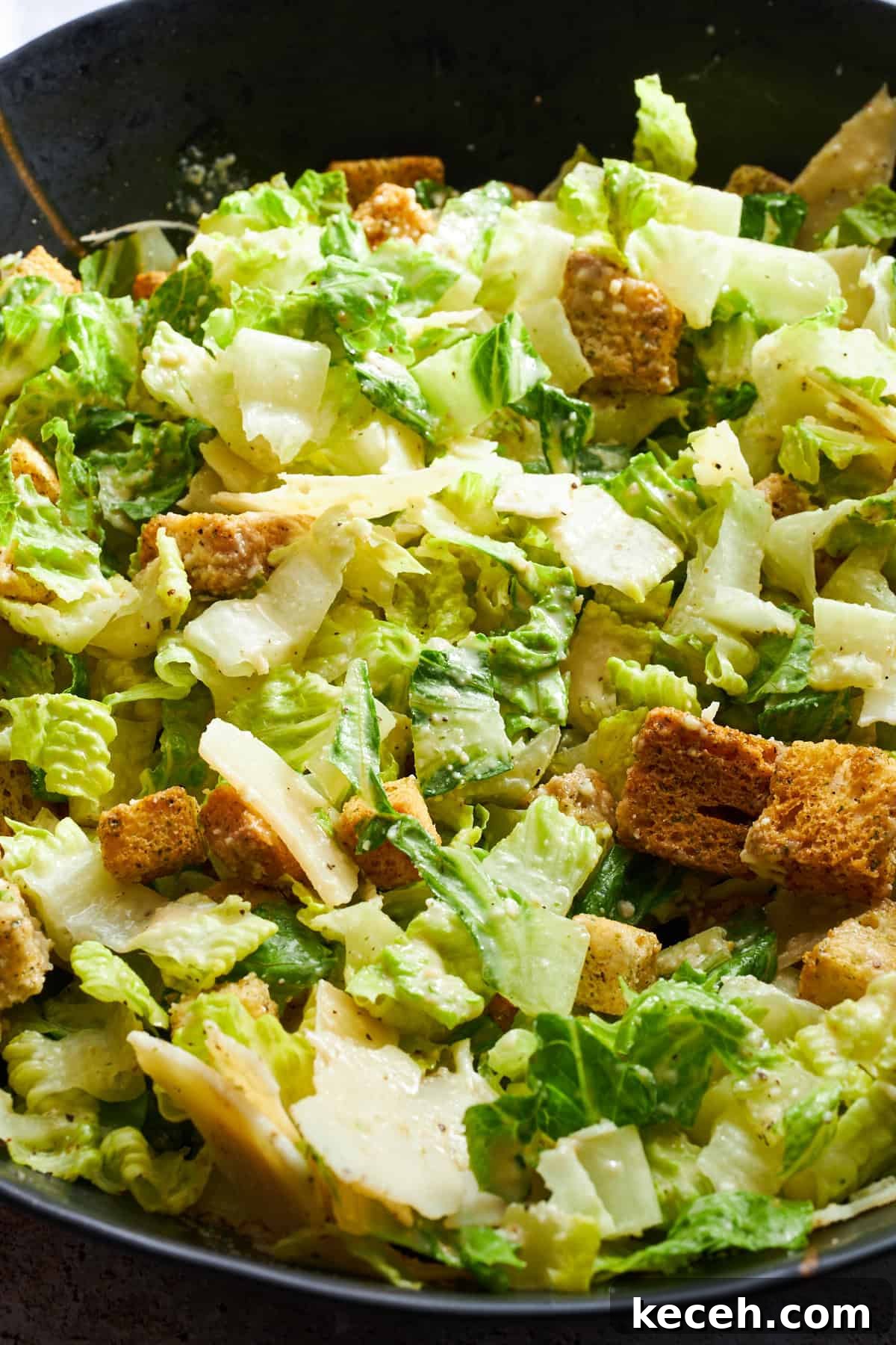 Classic Caesar Salad Recipe with Creamy Homemade Dressing 3 Close up image of a Caesar salad tossed with dressing.