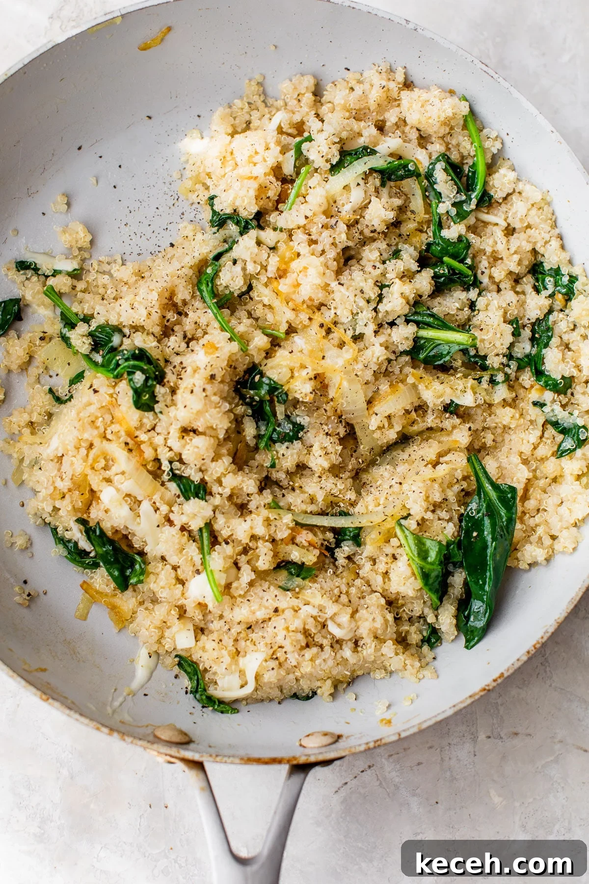 Caramelized Onion Quinoa Bowl with Herbed Lemon Dressing 5 quinoa, onions and spinach in a white skillet