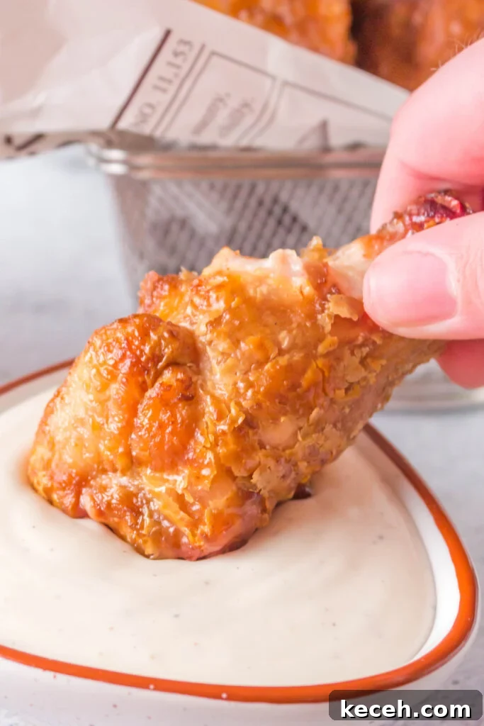Crispy Grilled Chicken Wings Recipe for Perfectly Charred Skin 5 hand dipping a chicken wing into sauce