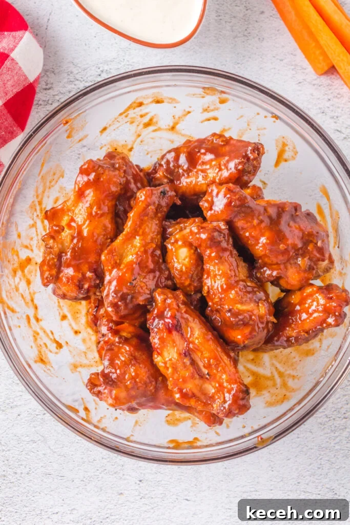 Crispy Grilled Chicken Wings Recipe for Perfectly Charred Skin 6 grilled crispy chicken wings in bowl being coated with bbq sauce