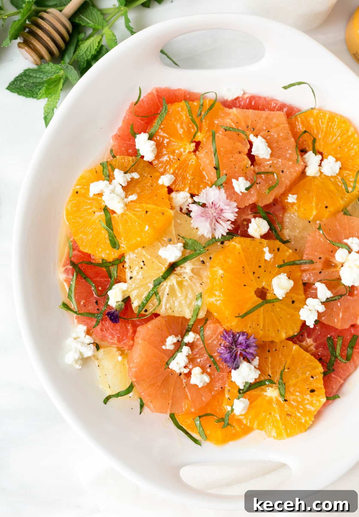 Citrus Salad with Honey-Balsamic Vinaigrette Recipe 2 citrus salad with crumbled goat cheese, herbs, and edible flowers in a white serving dish