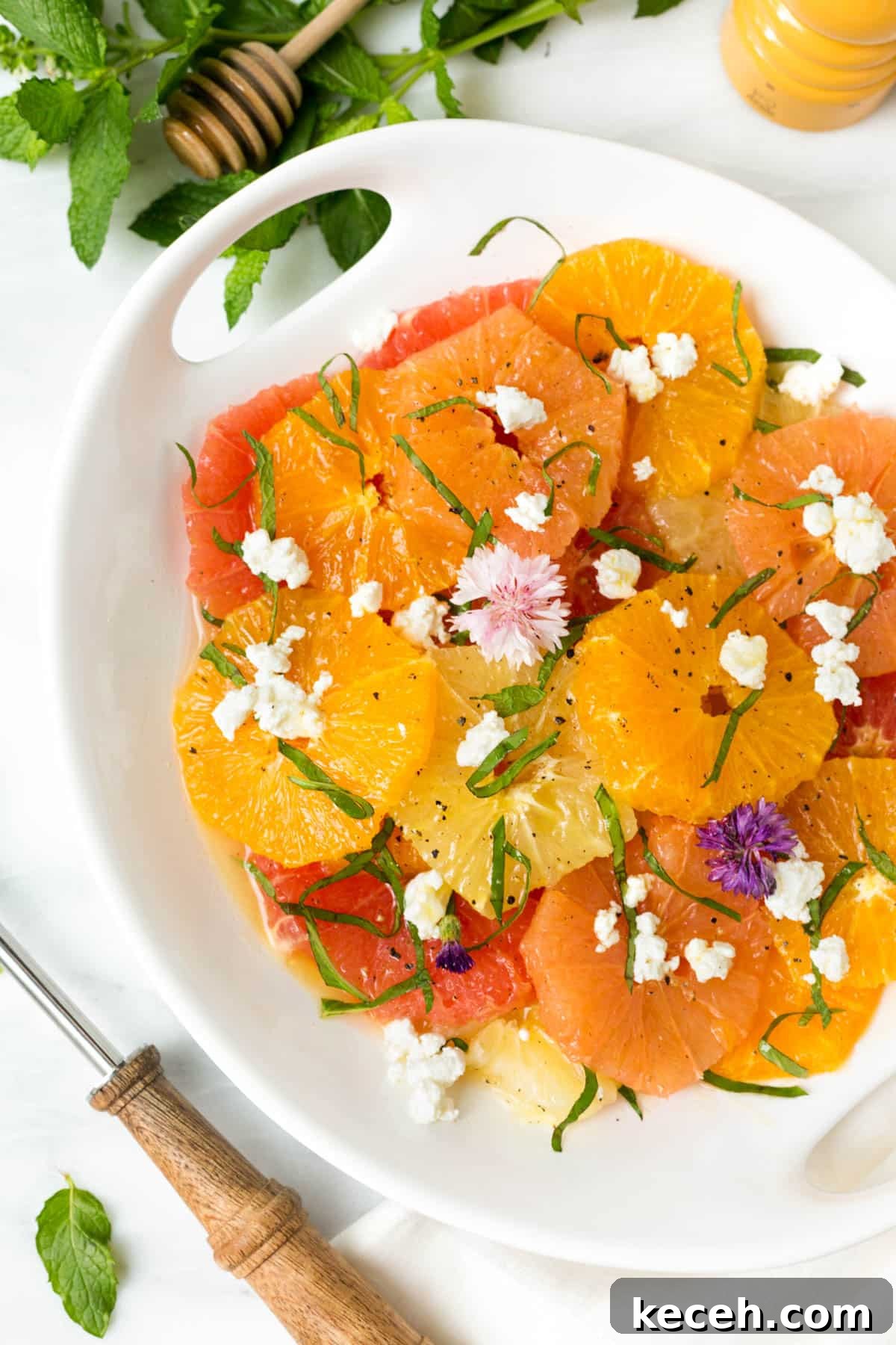 Citrus Salad with Honey-Balsamic Vinaigrette Recipe 6 mixed citrus salad with goat cheese and herbs in a white serving bowl on a white marble board
